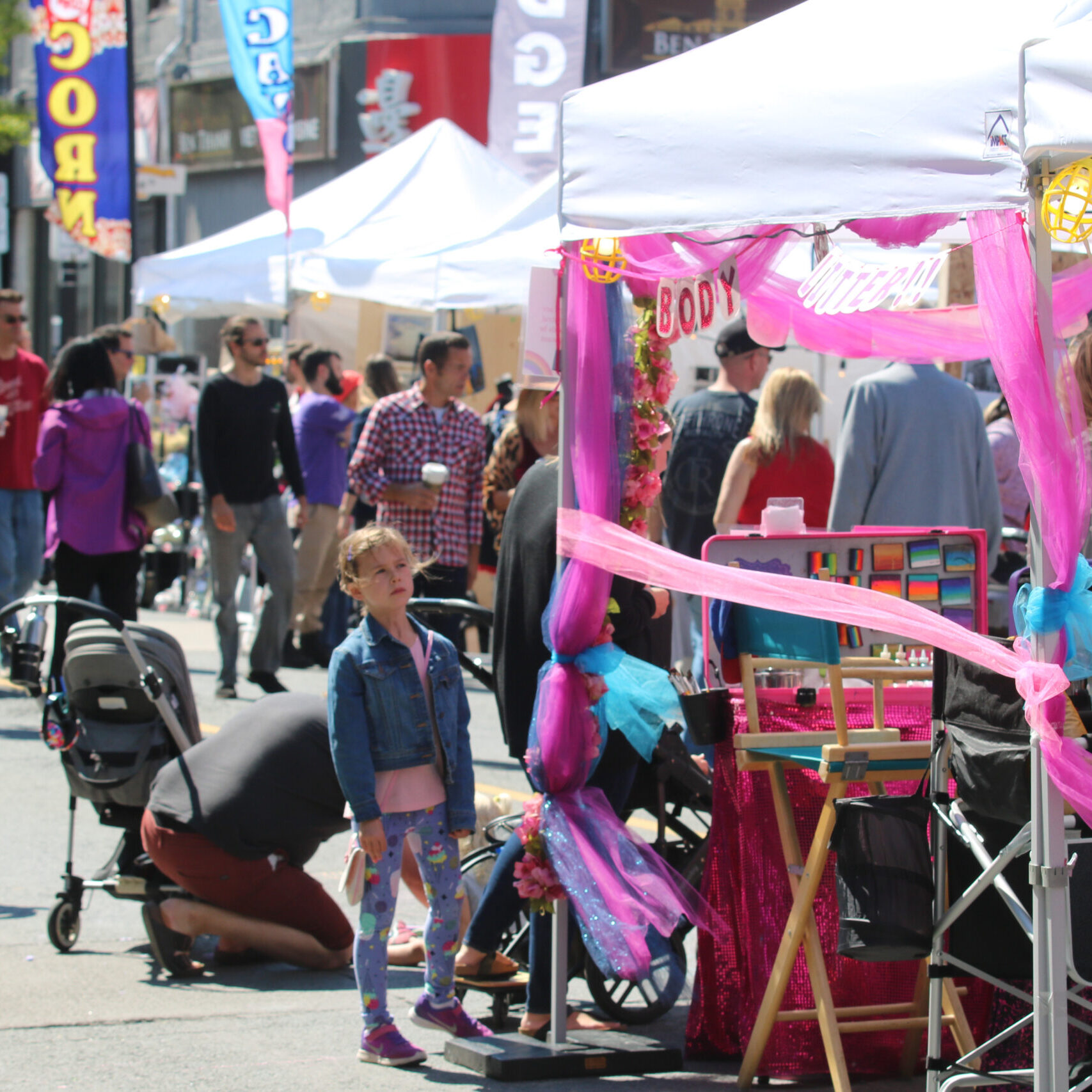 Little girl looking at a tented booth at a market