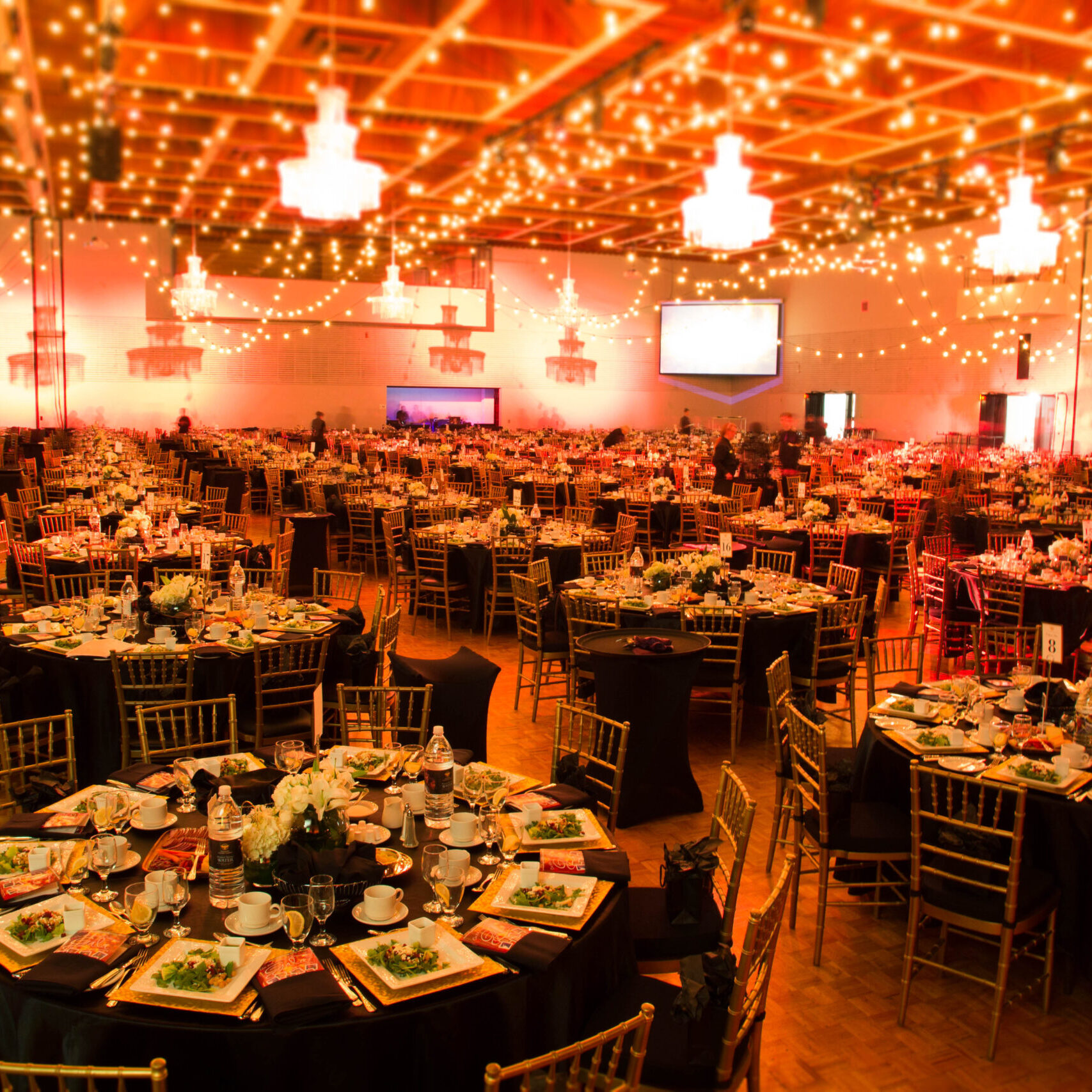 Inside a beautifully decorated banquet hall with lights and round tables