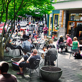 People outside sitting outside a cafe on chairs and tables