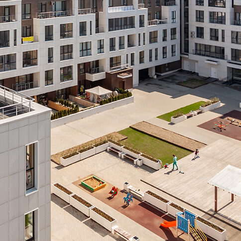 A rendering of modern apartment buildings in the shape of a U with walking space and greenery in the middle